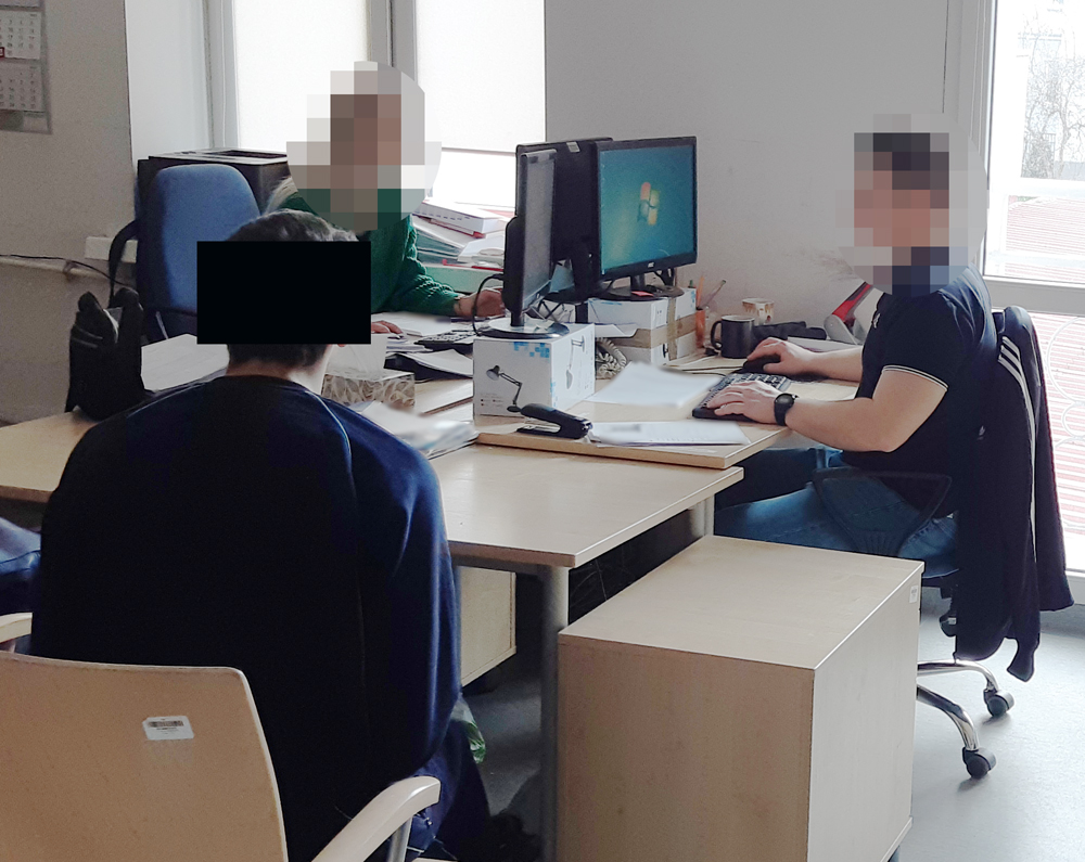 Trzy osoby pracują przy komputerach w nowoczesnym biurze.