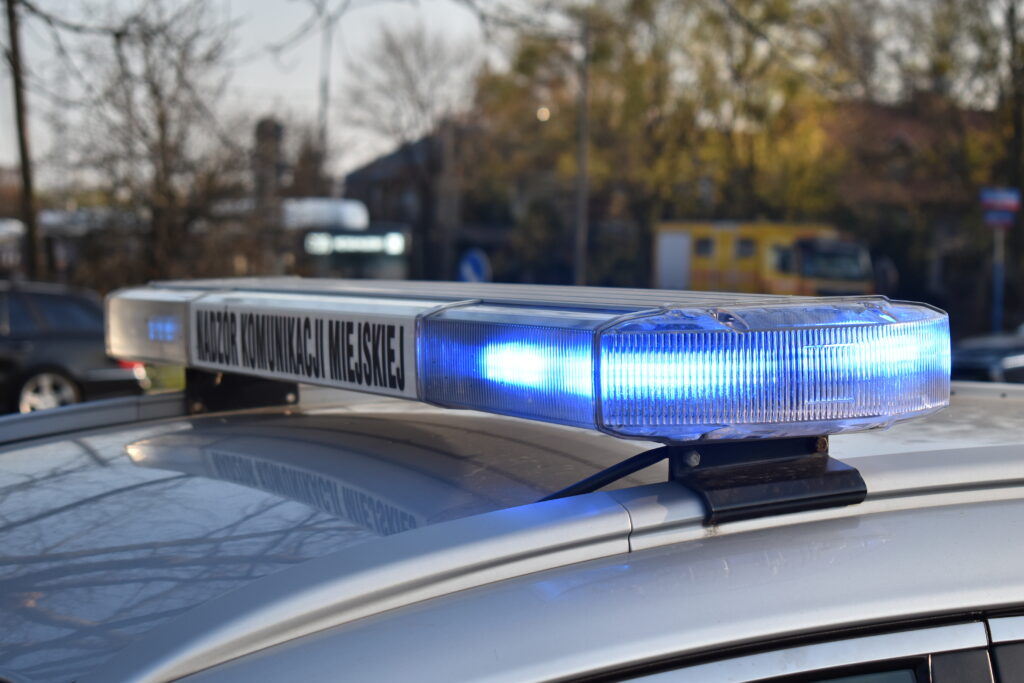 Niebieskie migające światła w pojeździe komunikacji miejskiej. Widoczny jest „Nadzór Komunikacji Miejskiej”.