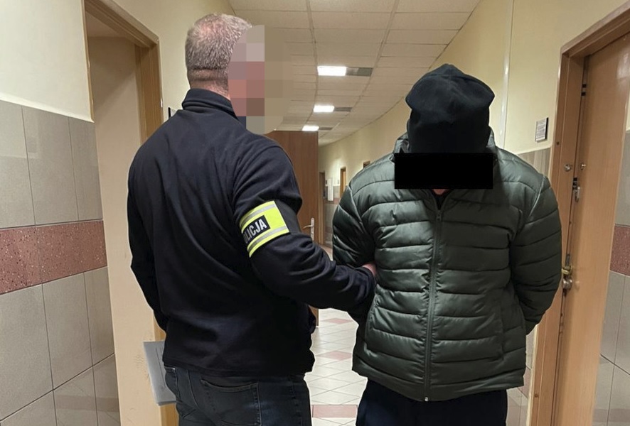 Policjant aresztujący podejrzanego na korytarzu.