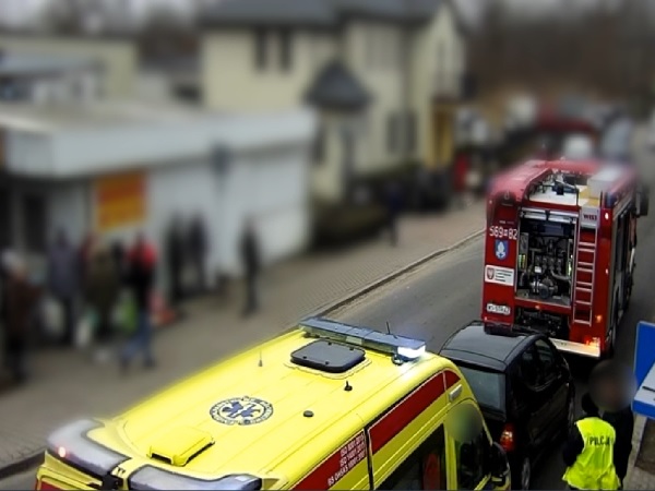 Pojazdy uprzywilejowane na miejscu wypadku: karetka pogotowia, wóz strażacki i uszkodzony samochód.