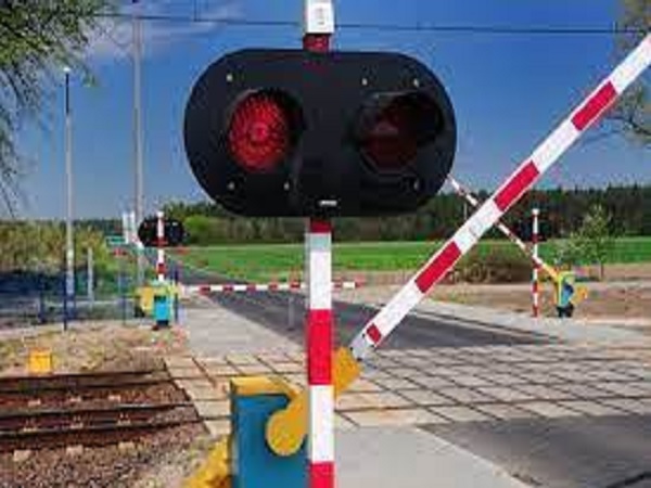 Szlabany na przejeździe kolejowym z migającymi czerwonymi światłami.
