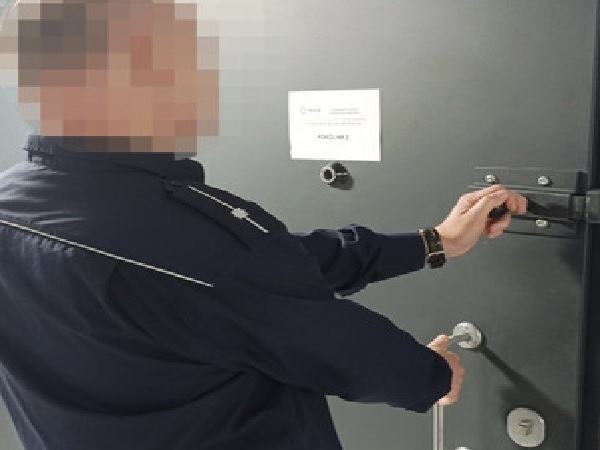 Ochroniarz otwiera solidne drzwi.