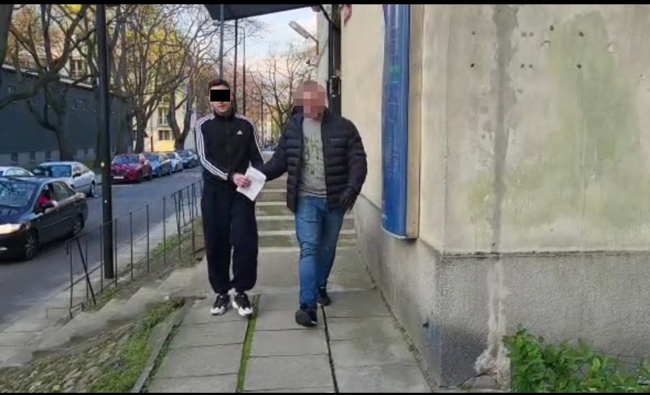 Dwóch mężczyzn w kajdankach eskortowanych przez policję.