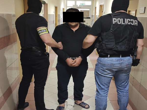 Policjanci aresztują podejrzanego w kajdankach na korytarzu. POLICJA