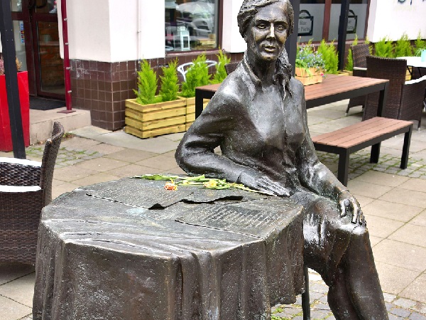 Brązowa statua autora siedzącego przy stole na zewnątrz