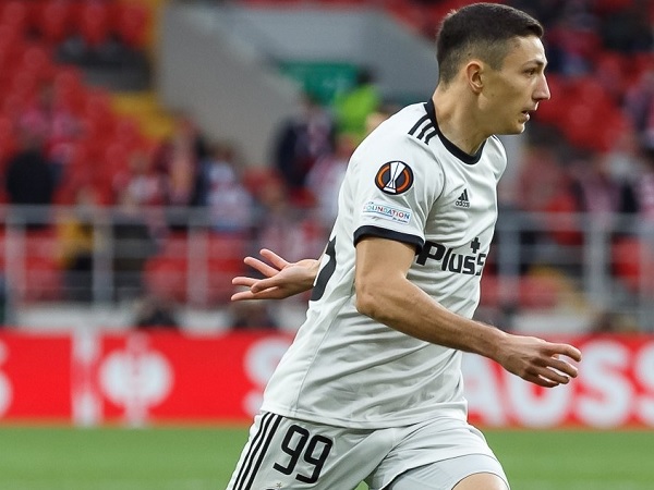 Piłkarz, numer 99, dryblujący piłkę podczas meczu.