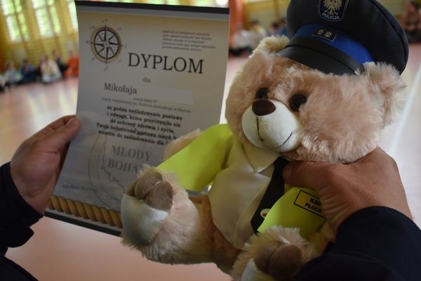 Miś w mundurze policyjnym otrzymuje dyplom „Młodego Bohatera”.