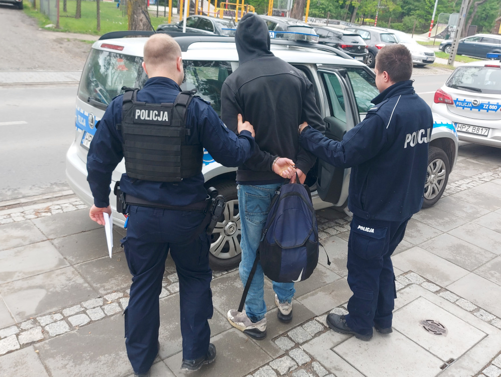 Dwóch polskich policjantów aresztuje podejrzanego, na mundurach widoczny jest napis „Policja”.