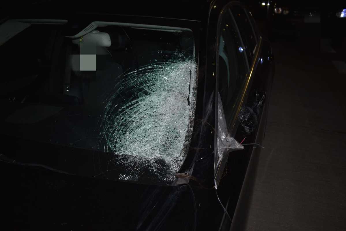 Rozbita przednia szyba czarnego samochodu po wypadku. Uszkodzenie samochodu, naprawa szyb samochodowych.