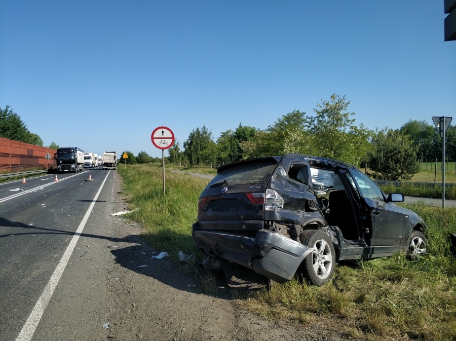 Uszkodzony czarny SUV po wypadku samochodowym na drodze z ciężarówkami