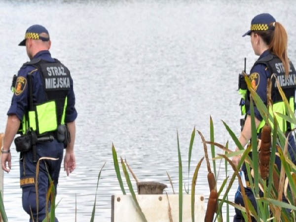 Dwóch funkcjonariuszy Policji Miejskiej „Straż Miejska” prowadzi śledztwo nad jeziorem.
