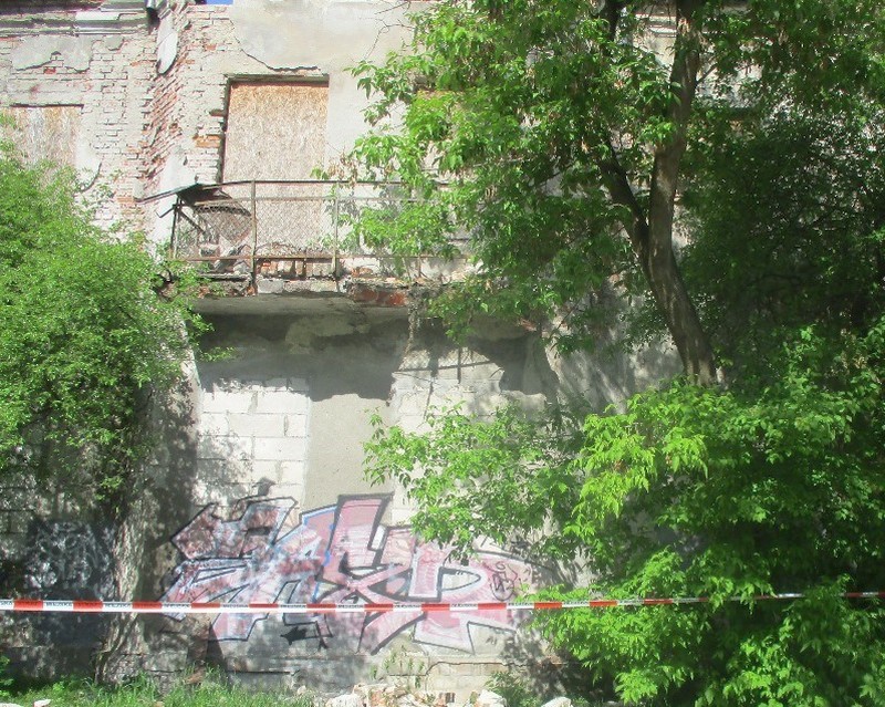 Stary ceglany budynek z graffiti i przerośniętymi drzewami