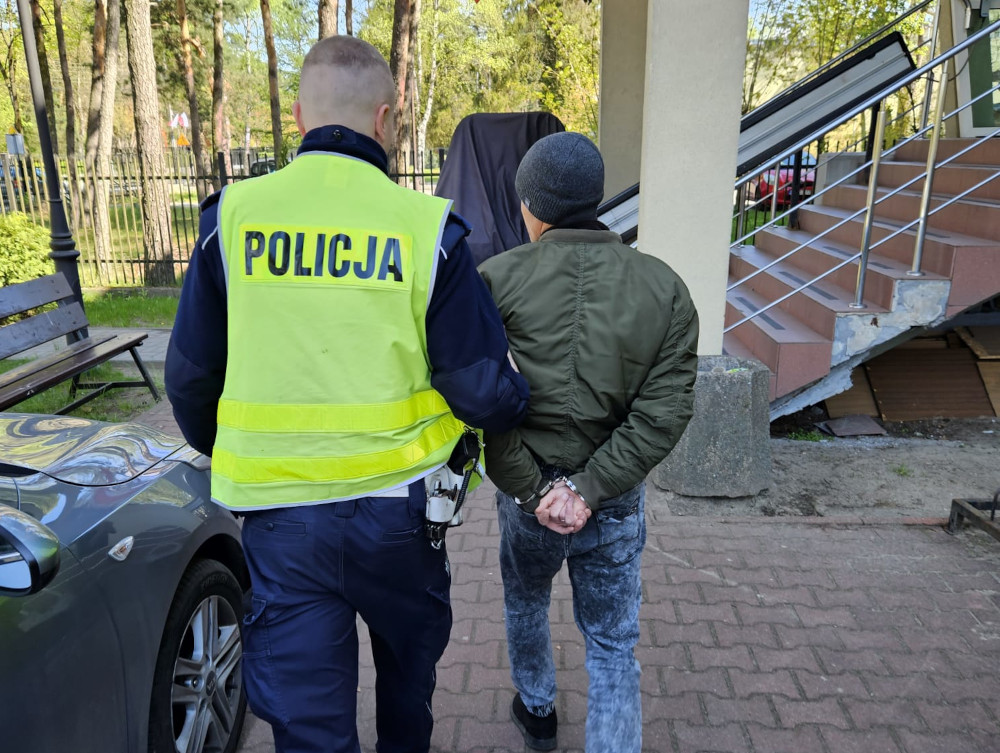 Policjant aresztujący podejrzanego, widoczne kajdanki. POLIJA