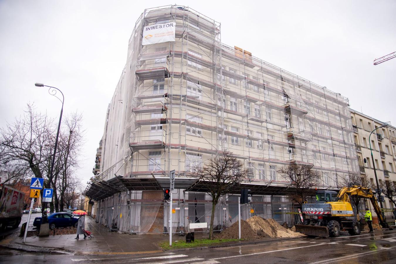 Renowacja budynku wielopiętrowego, widoczne rusztowanie i sprzęt budowlany. Na budynku baner „INWESTOR”.