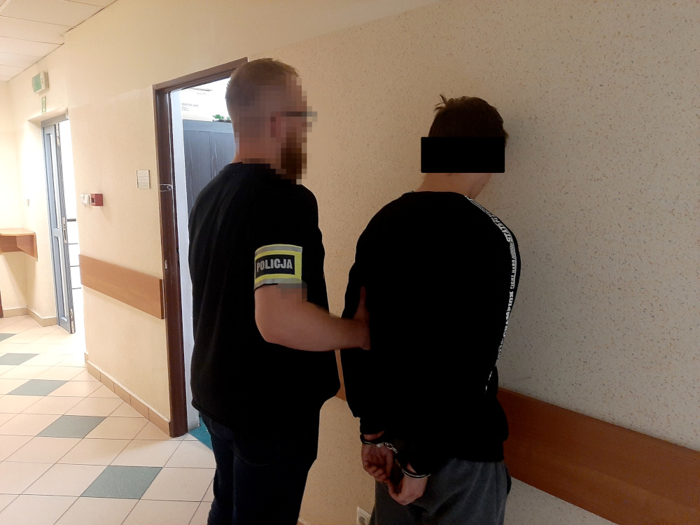 Policjant aresztujący podejrzanego, widoczne kajdanki.