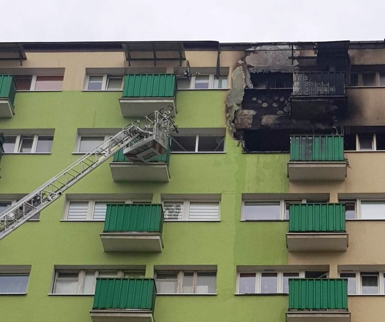 Uszkodzenia balkonu w budynku mieszkalnym spowodowane pożarem, widoczna drabina wozu strażackiego