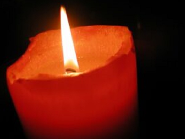 Pojedyncza czerwona świeca płonąca jasno w ciemności