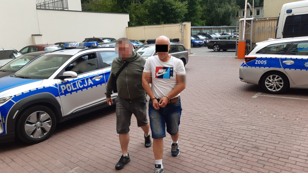 Policja aresztuje mężczyznę w kajdankach, eskortowanego przez funkcjonariusza. POLICJA