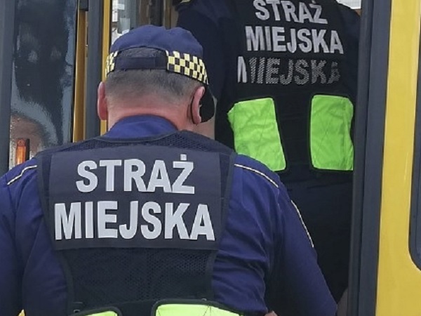 Dwóch polskich strażników miejskich w mundurach. Na ich kamizelkach widać napis „Straż Miejska”.