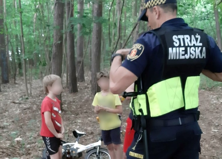 Funkcjonariusz policji miejskiej rozmawia z dziećmi w lesie