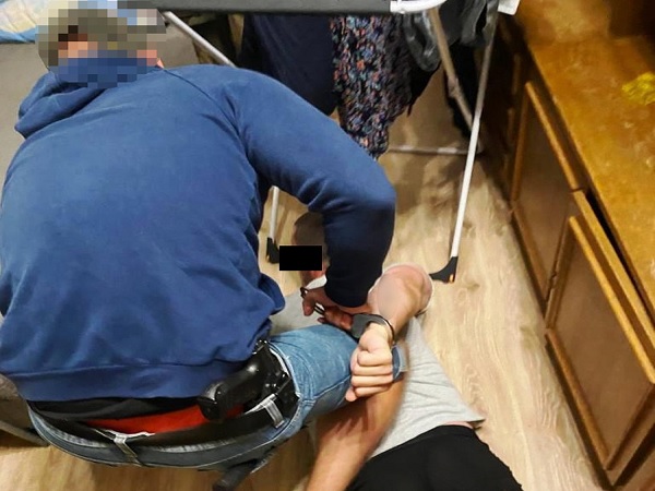 Policjant aresztujący podejrzanego z kajdankami na rękach.