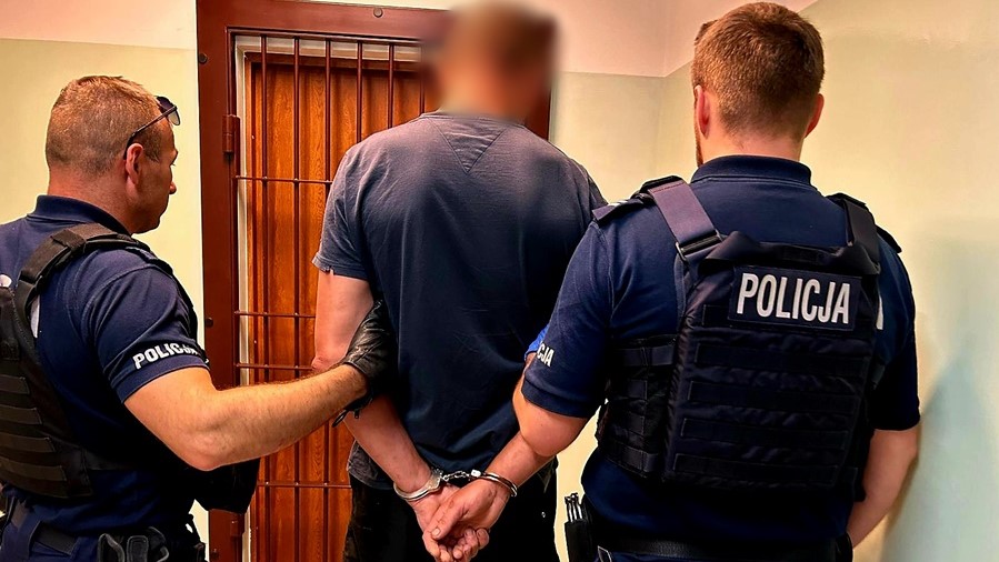 Policjanci zatrzymują podejrzanego w kajdankach.