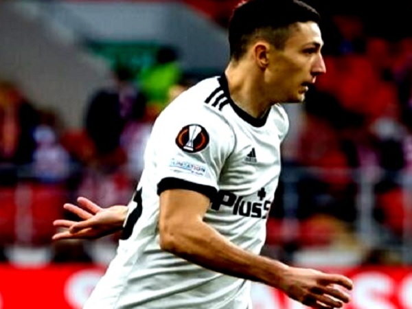 Piłkarz świętujący zdobycie gola, ubrany w białą koszulkę z czarnymi akcentami.