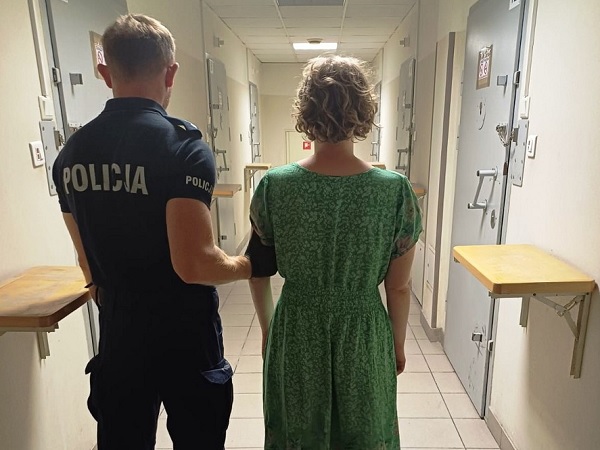 Policjant eskortujący kobietę korytarzem więziennym. POLICJA