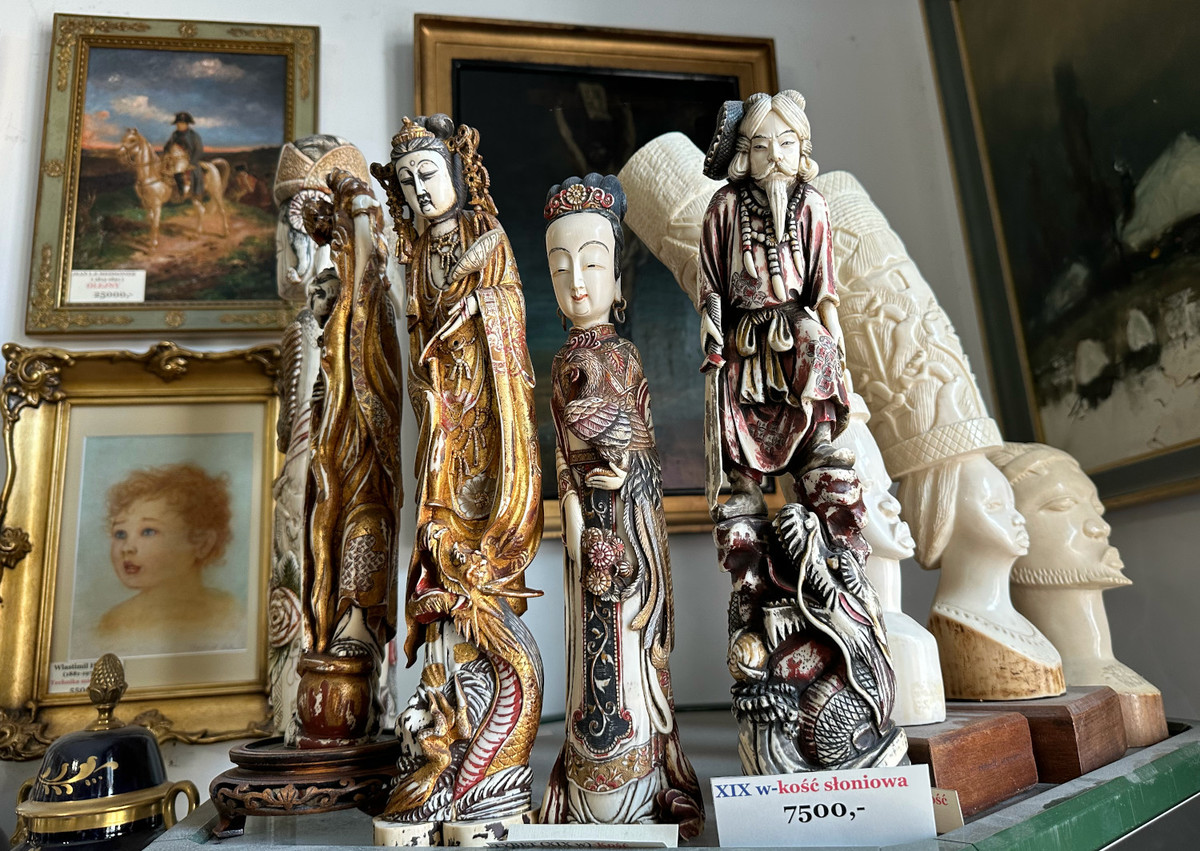 Antyczne rzeźby z kości słoniowej przedstawiające azjatyckie figurki i metka z ceną „7500,-”.