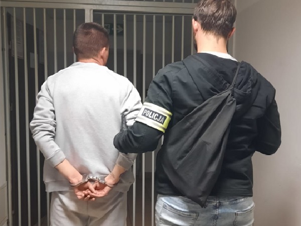 Policjant aresztujący podejrzanego w kajdankach.