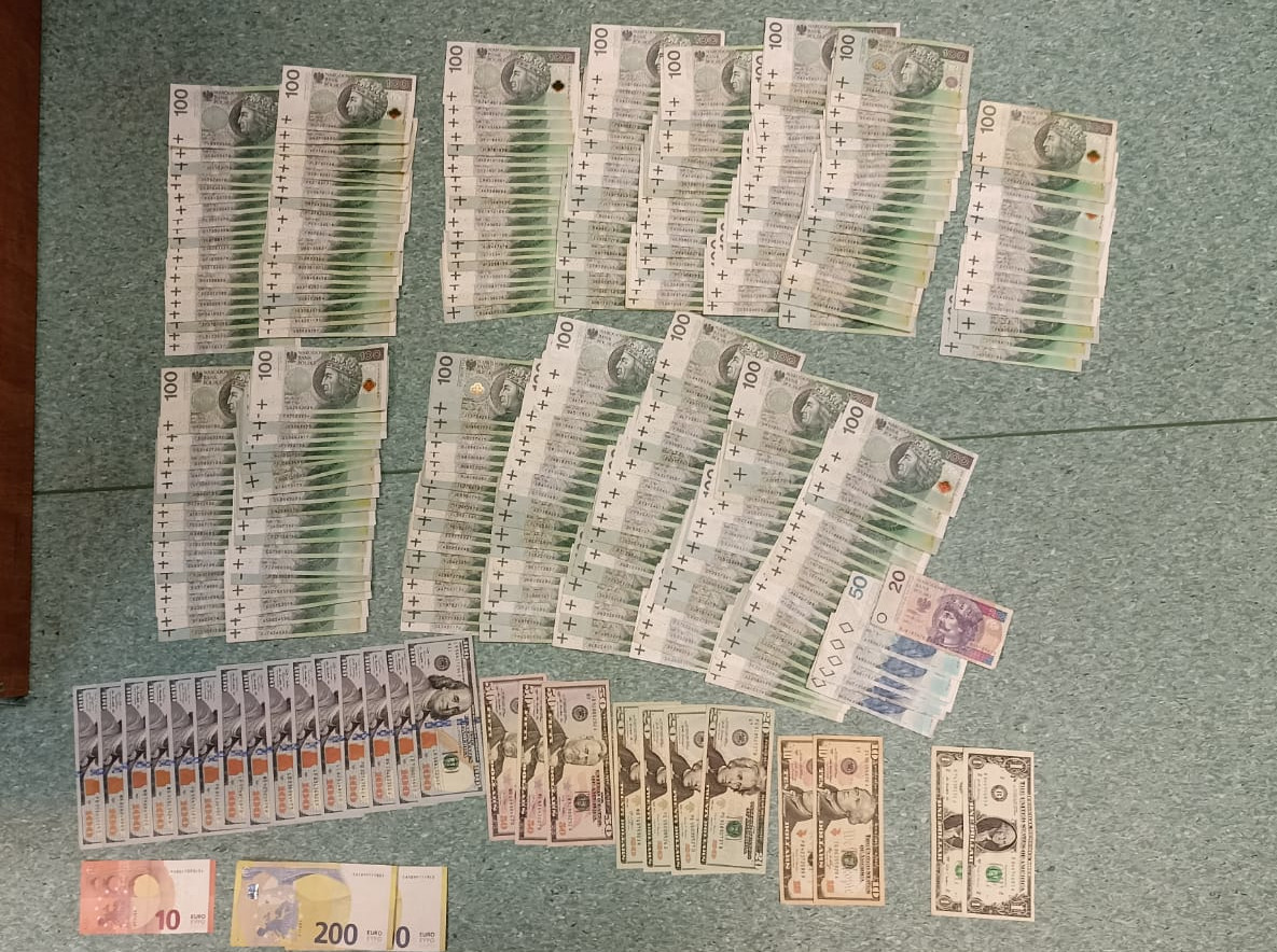 Stosy dolarów amerykańskich i złotych polskich ułożone na stole. Zarekwirowana gotówka.