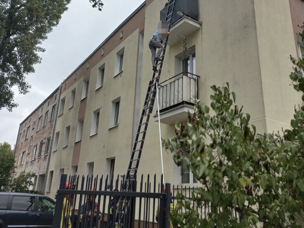 Strażacy używają wydłużonej drabiny, aby uratować osobę z budynku mieszkalnego.