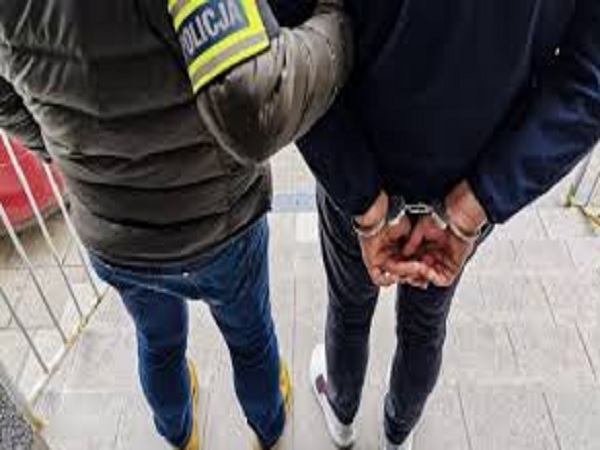 Policjant aresztujący podejrzanego, widoczne kajdanki.