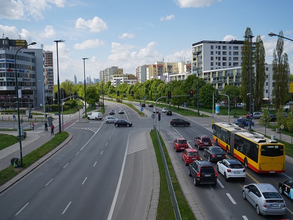 Ruchliwa ulica miejska z samochodami, autobusami i nowoczesnymi budynkami