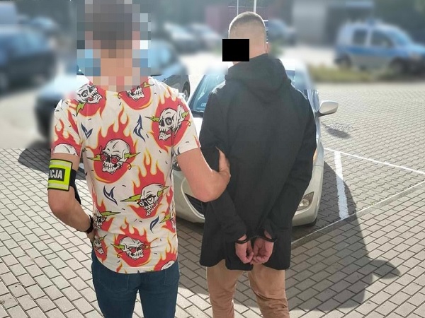 Policjant aresztujący podejrzanego, widoczne kajdanki.