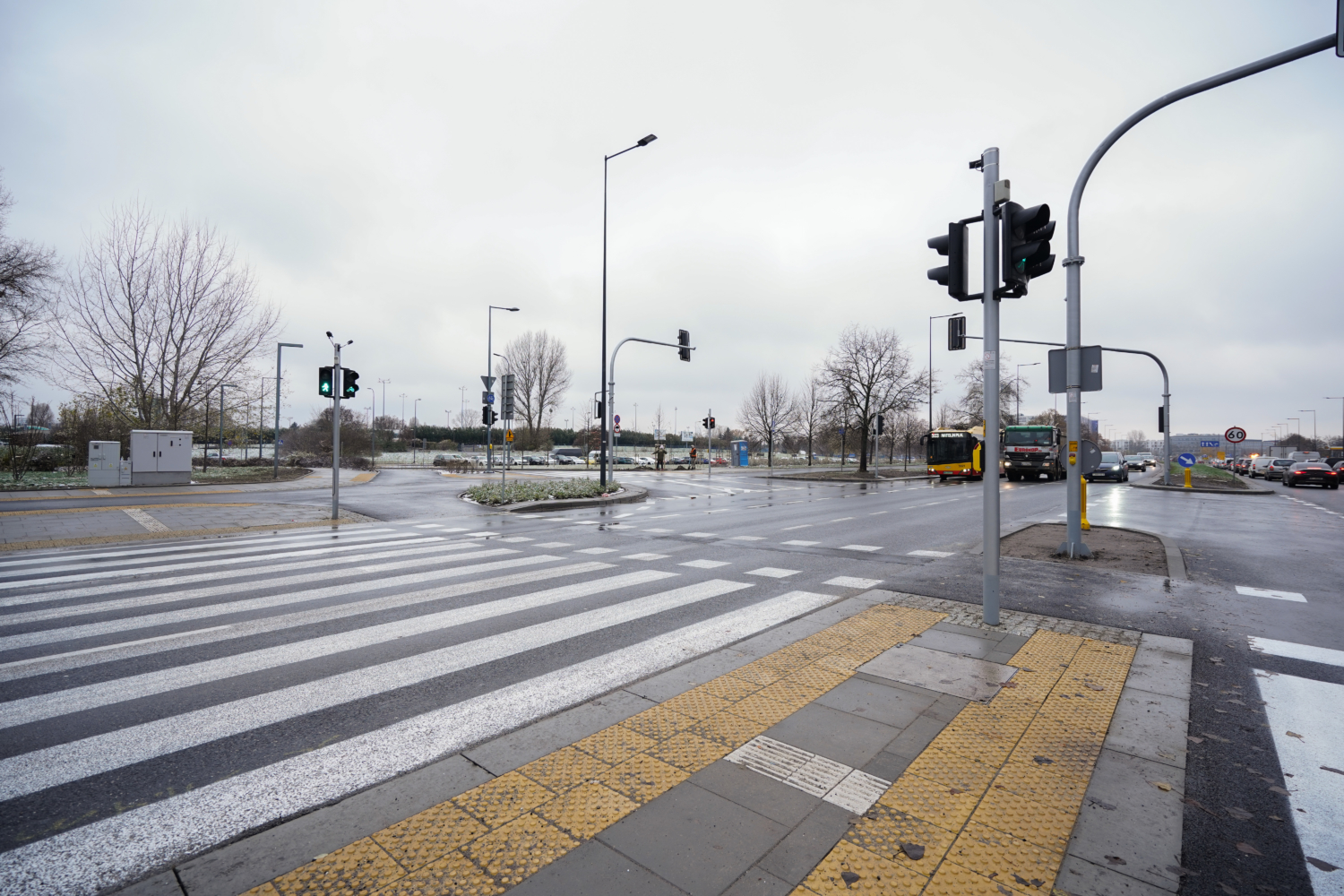Puste skrzyżowanie z przejściem dla pieszych, sygnalizacją świetlną i autobusami.