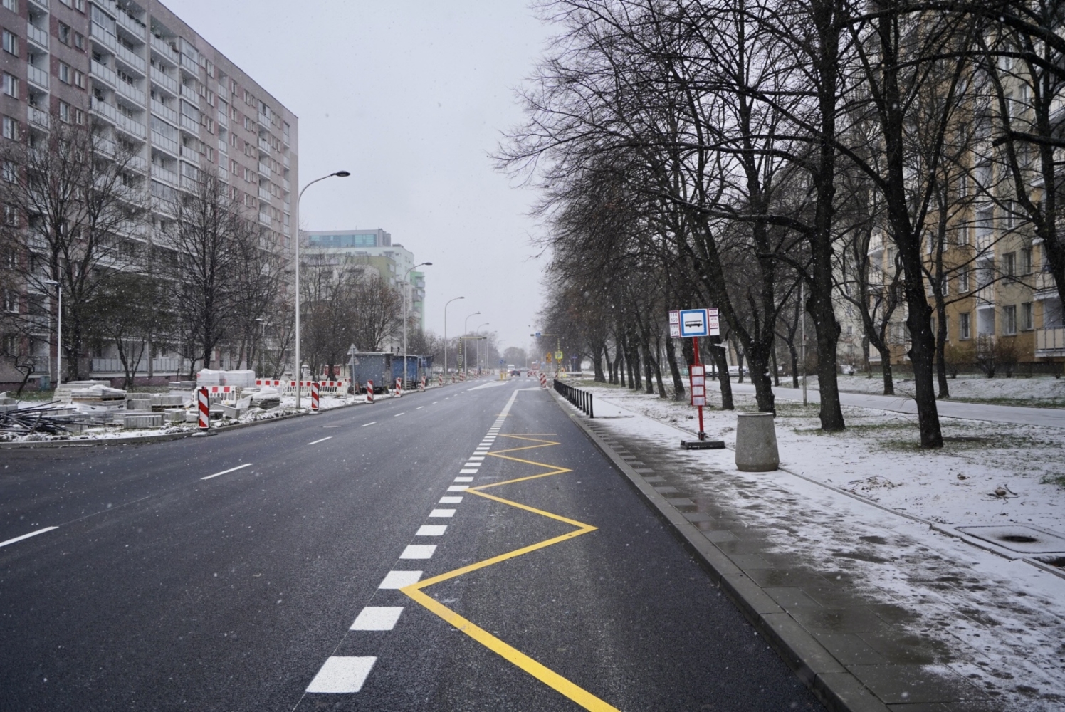 Pusta, pokryta śniegiem ulica w mieście z przystankiem autobusowym