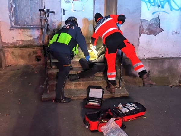 Ratownicy medyczni udzielają pomocy osobie znajdującej się na schodach.