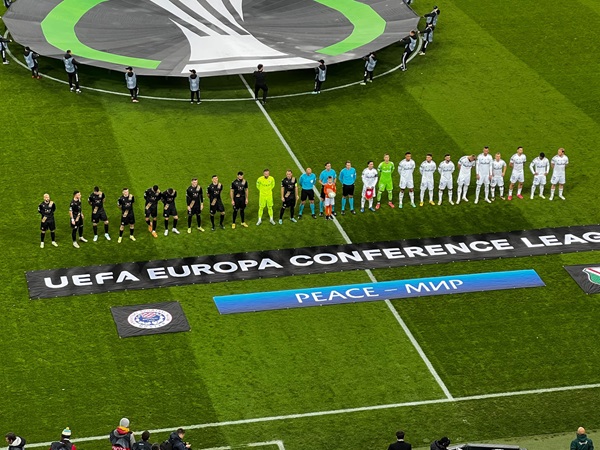 Zespoły Ligi Konferencji Europejskiej UEFA ustawiają się przed meczem, na transparentach widnieje napis „Pokój – Мир.