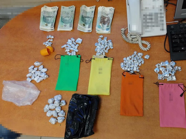 Zarekwirowane narkotyki, gotówka (100 zł) i torby na stole. Dowody w sprawie narkotykowej.