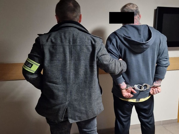 Policjant aresztujący podejrzanego w kajdankach.