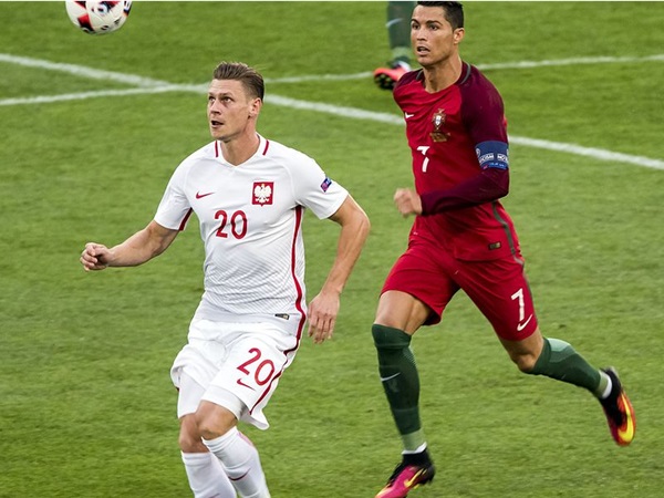 Cristiano Ronaldo i Kamil Grosicki z Polski walczą o piłkę podczas meczu piłki nożnej.