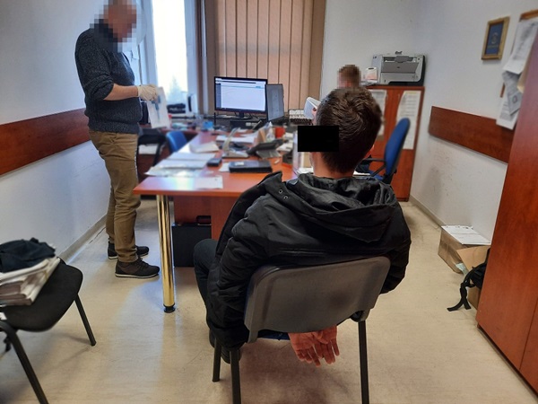 Pokój przesłuchań policji: Podejrzany ze związanymi rękami, obecni funkcjonariusze.