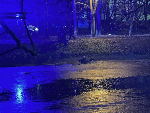 Ratownicy w nocy wyciągają mężczyznę z rzeki.