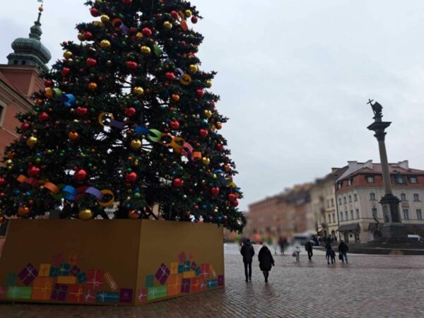 Duża choinka na warszawskim Starym Mieście, udekorowana kolorowymi ozdobami i wstążkami.