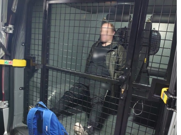 Osoba w bezpiecznej klatce transportu policyjnego.