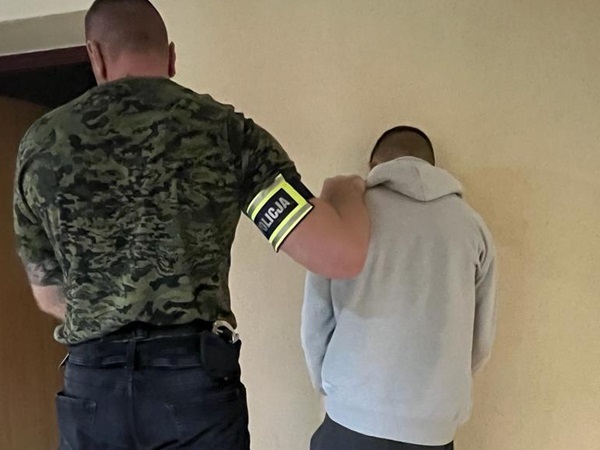 Policjant zatrzymujący podejrzanego przy ścianie