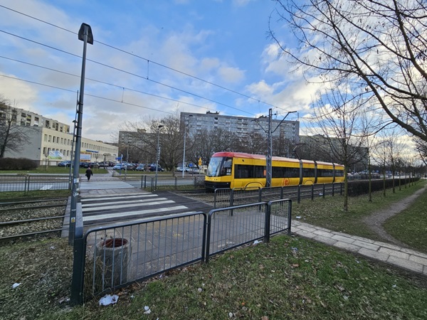 Żółty tramwaj na torach miejskich w pobliżu przejścia dla pieszych