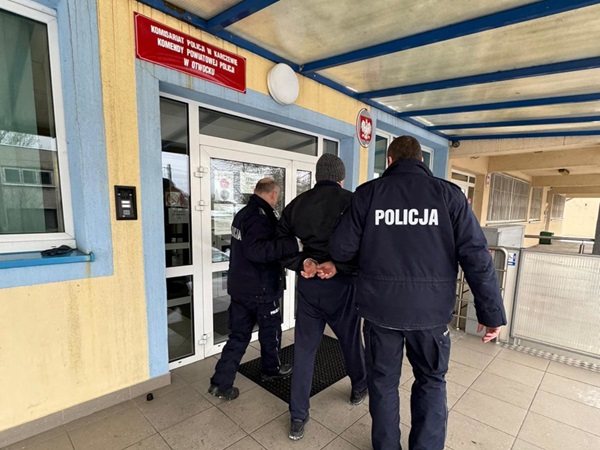 Policjanci eskortujący podejrzanego przed komisariatem policji w Polsce. POLICJA