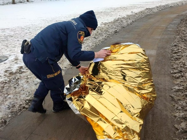 Ratownik owija osobę złotym kocem termicznym.